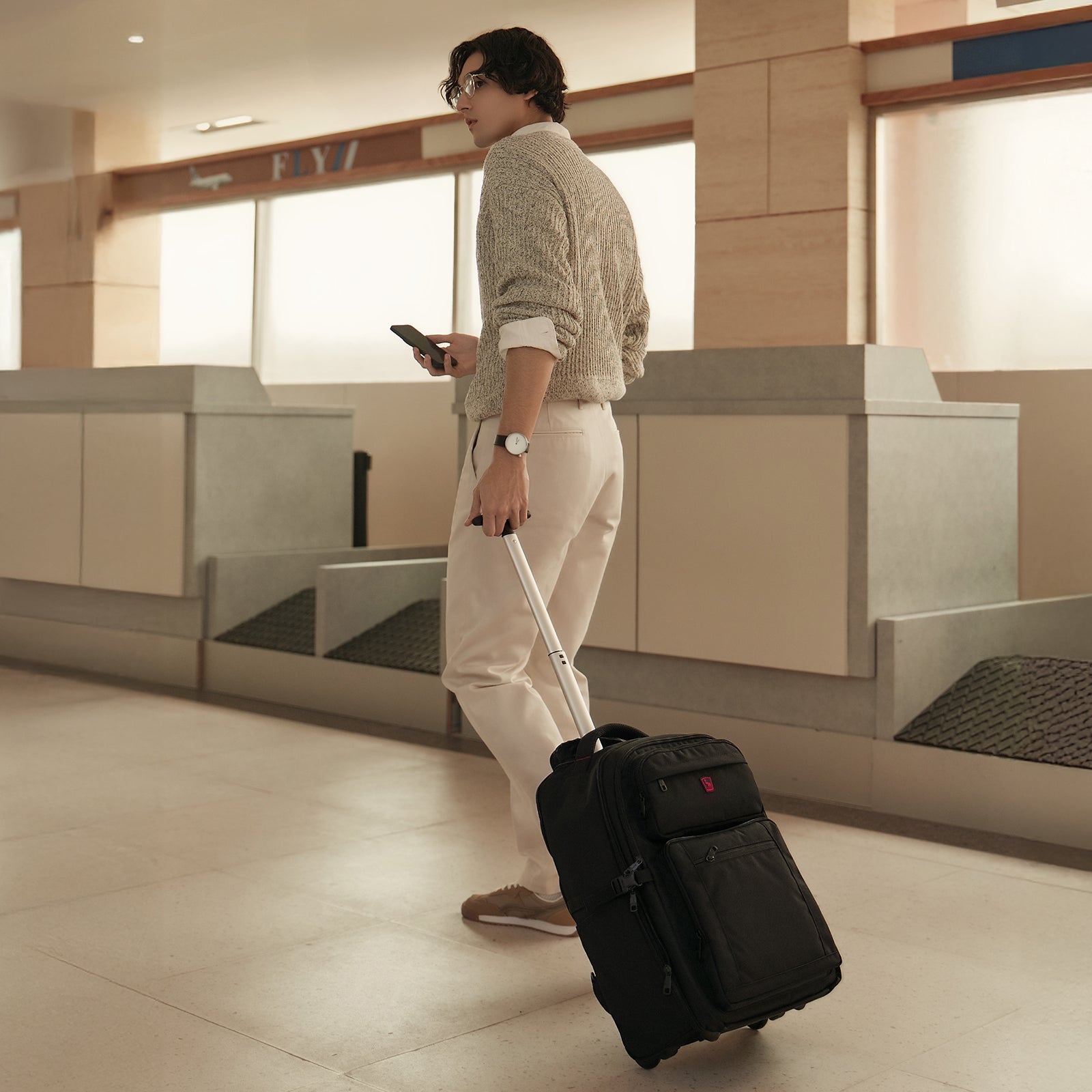 Business traveler rolling backpack through airport