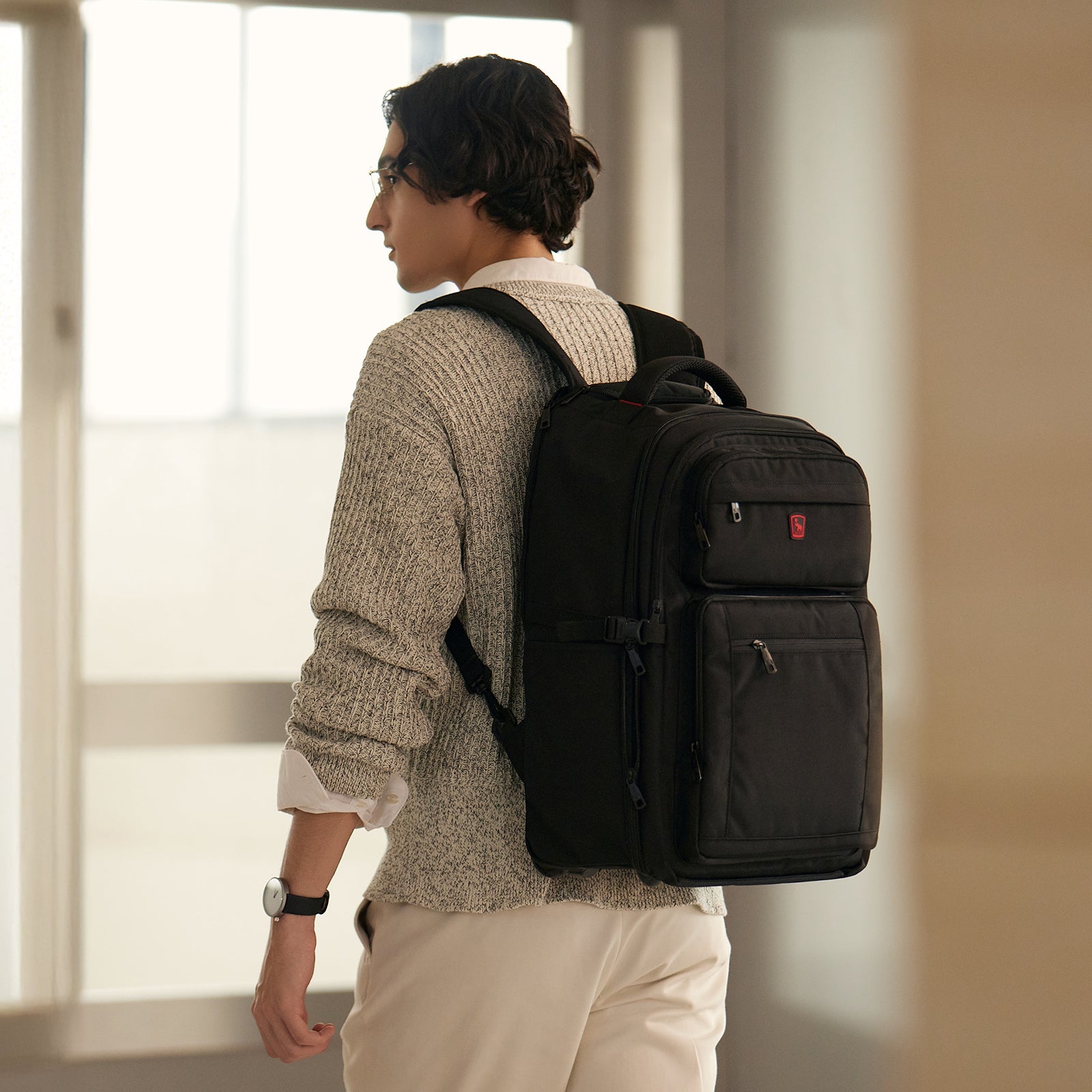 Business traveler carrying wheeled backpack walk through the airport
