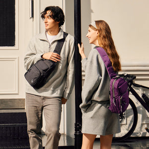 OIWAS purple sling bag worn crossbody by man & woman during urban commute